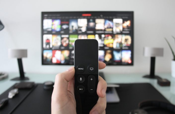 hand holding remote with TV in background