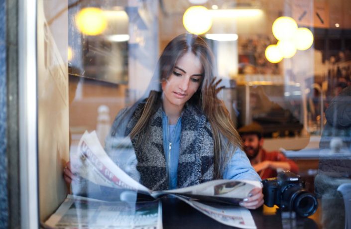 woman reading newspaper through window